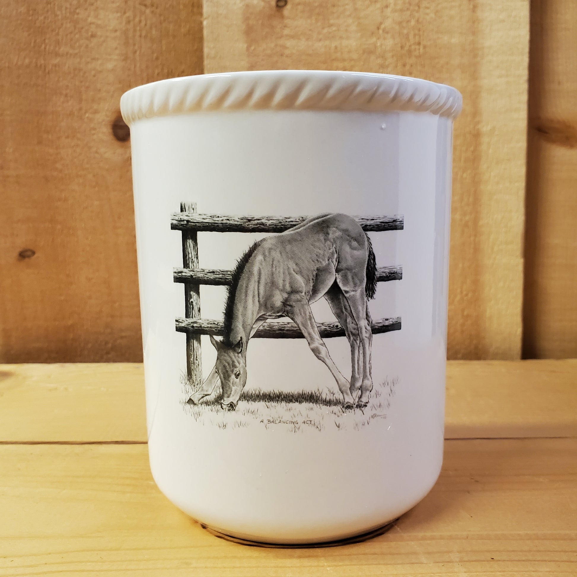 a white ceramic utensil holder with western pencil art featuring a foal eating grass