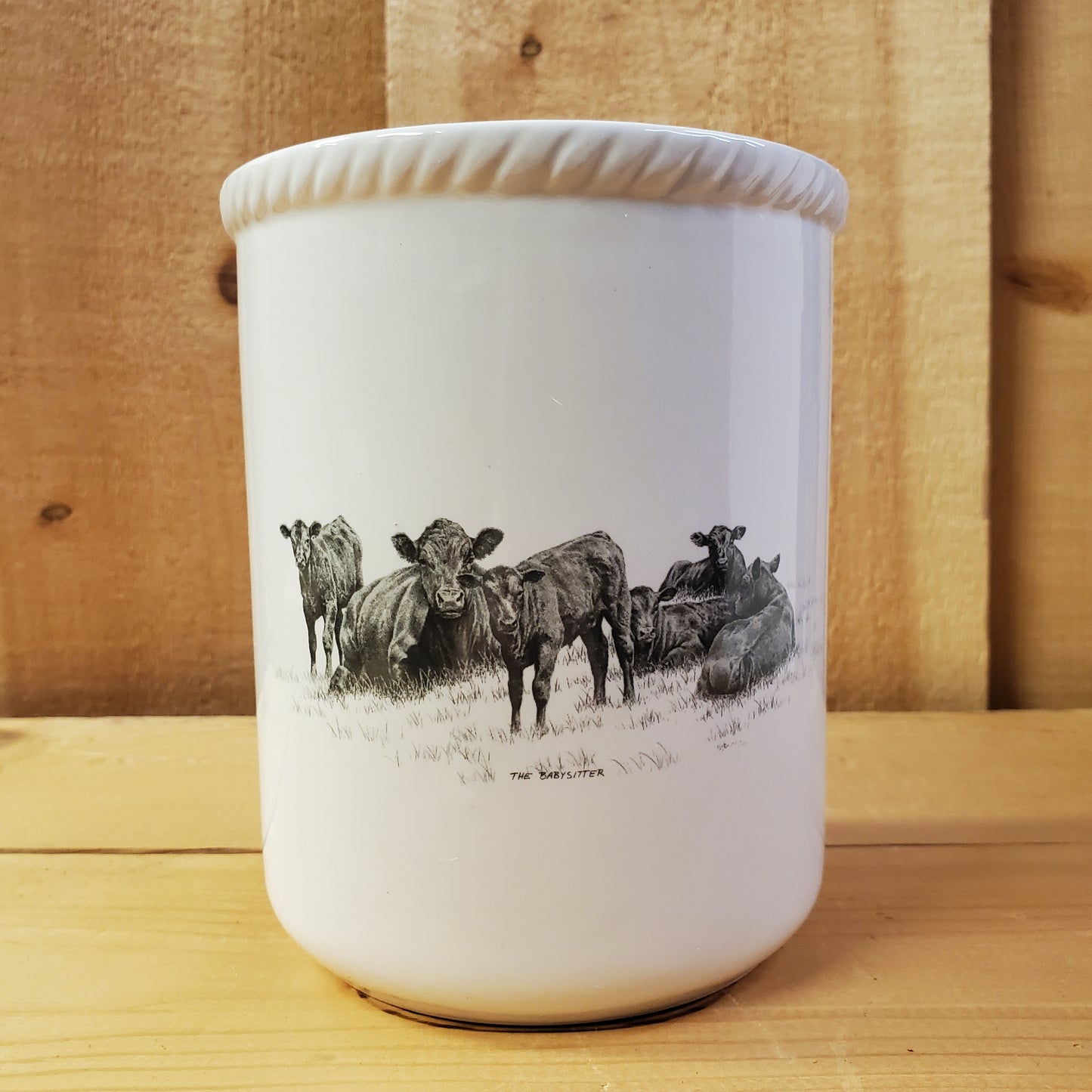 a white ceramic utensil holder with western pencil art featuring resting cows