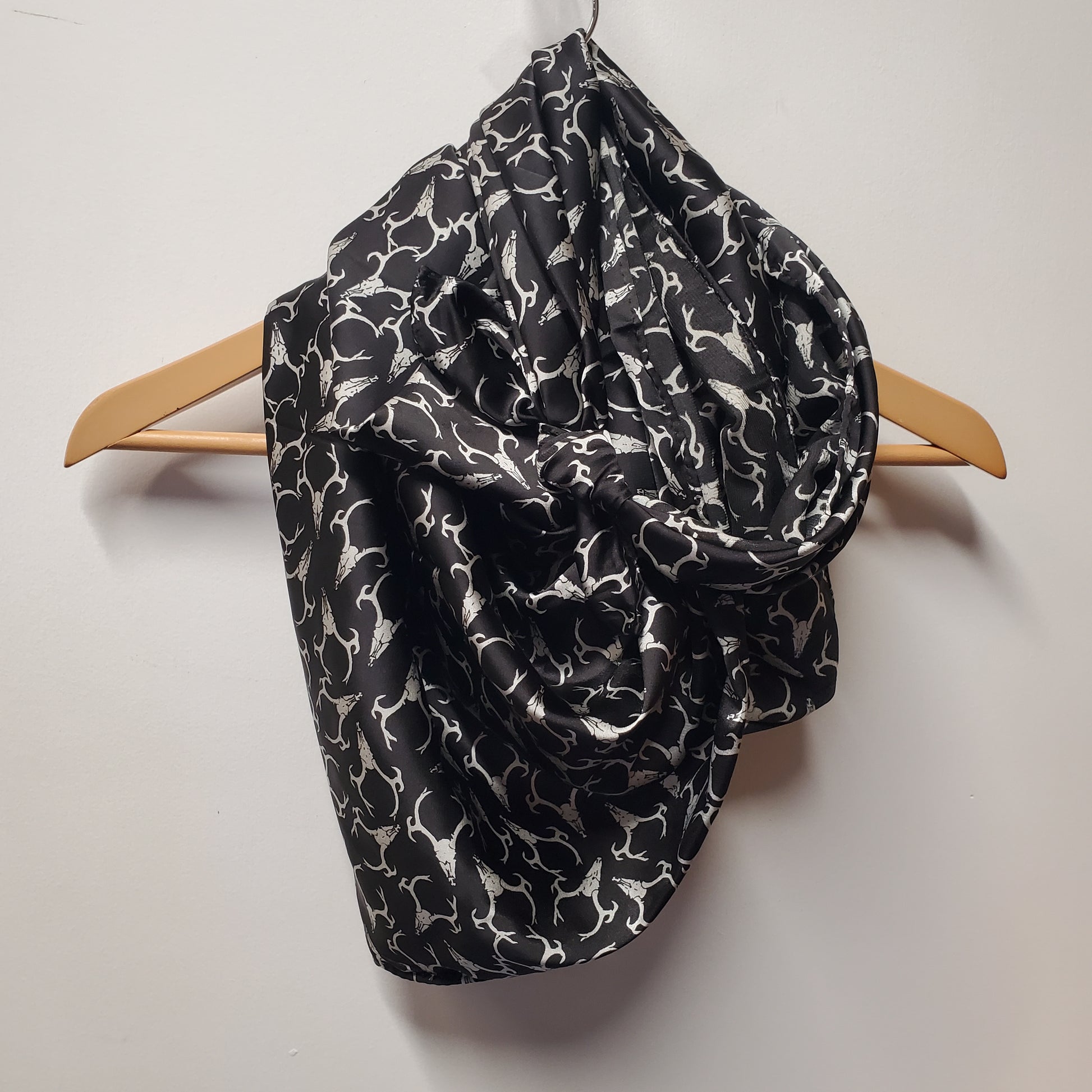Silk scarf hanging on coat hanger with deer skull print on a white background