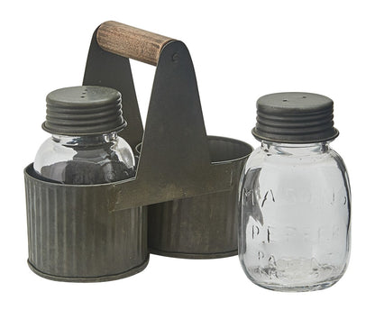 A rustic metal salt and pepper shaker set with a dark gray painted steel carrier, a wooden handle, and two clear glass bottles with dark gray screw-on lids by Park Designs, shown on a white background.