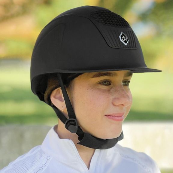 Person wearing a black riding helmet with a blurred natural background
