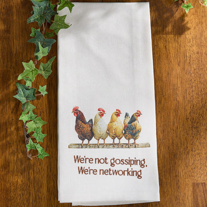 White towel with chicken illustration and text on a wooden surface with ivy