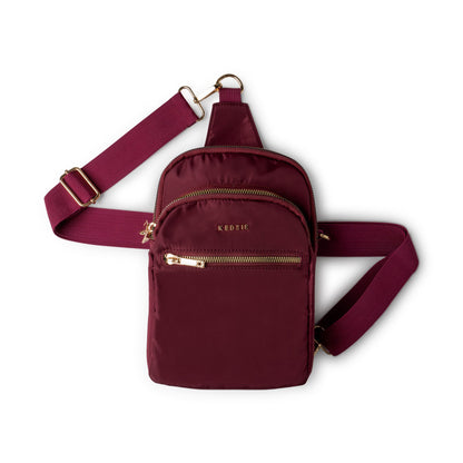 Maroon Kedzie crossbody bag with gold zippers on a white background