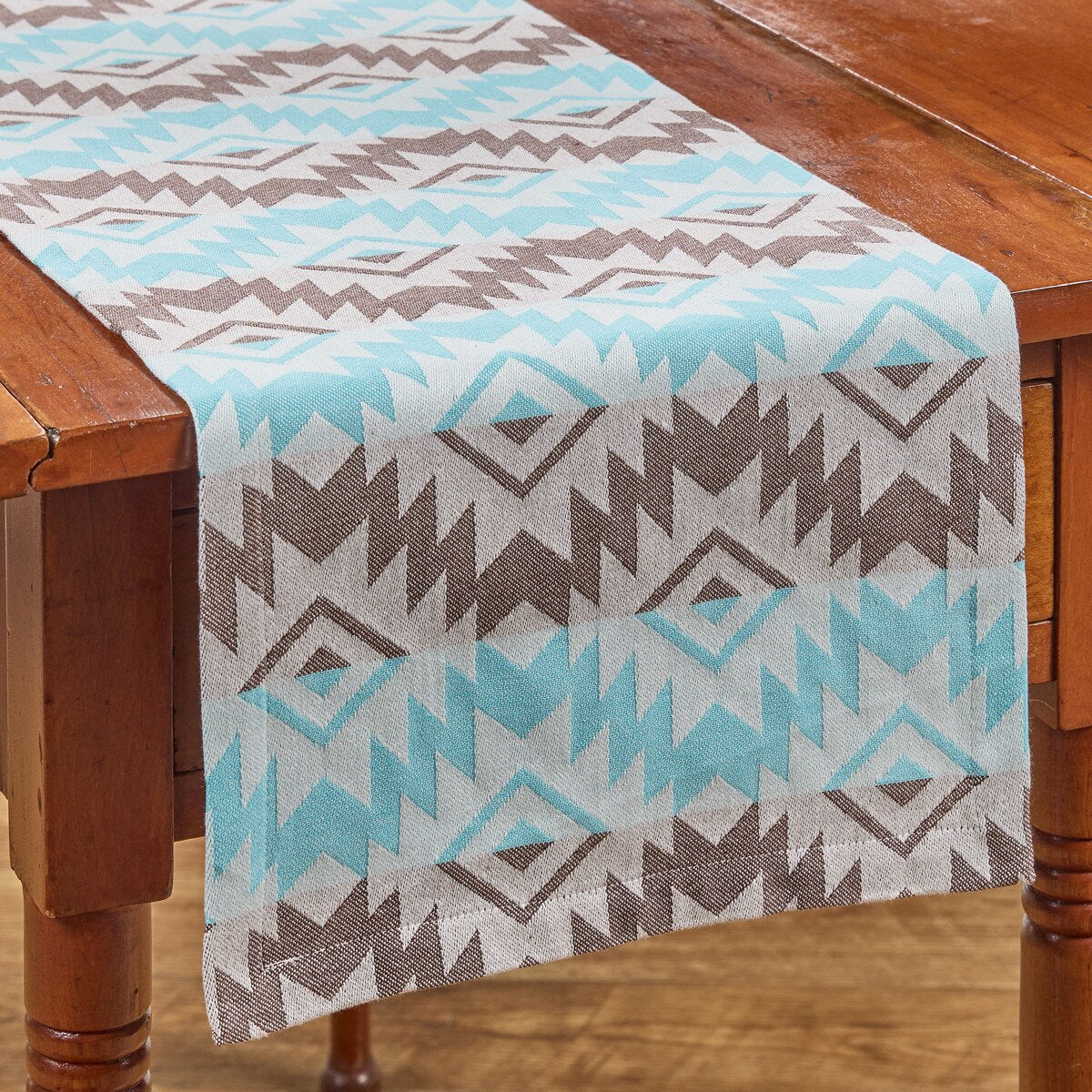 Table runner with teal aztec geometric pattern on a wooden table