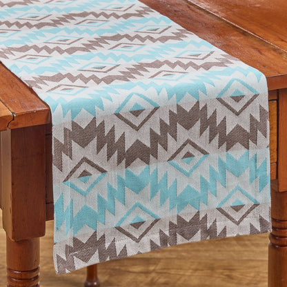 Table runner with teal aztec geometric pattern on a wooden table