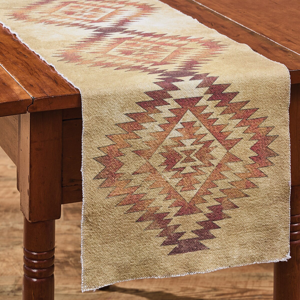 tan colored Table runner with orange axtec pattern on a wooden table