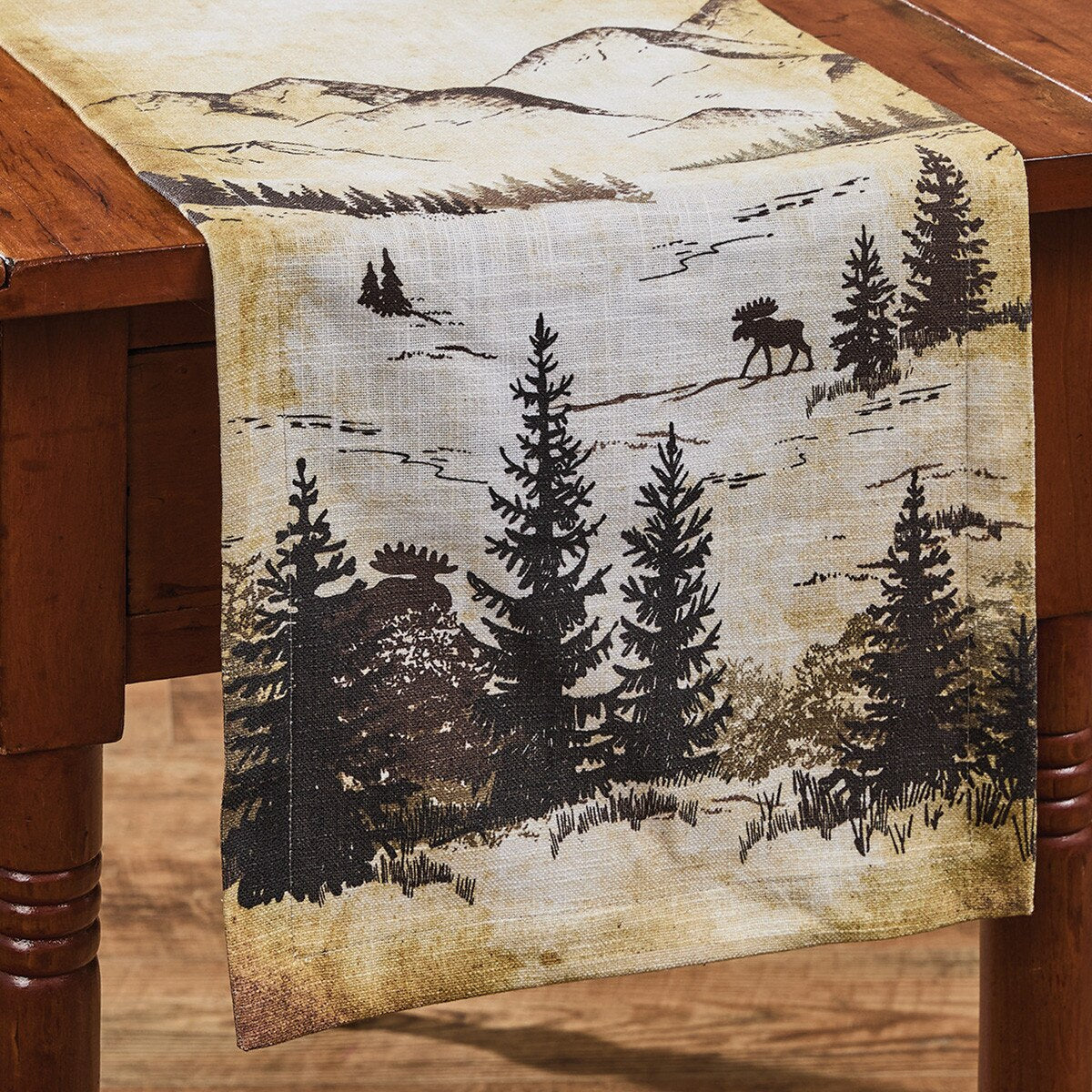 Table runner with moose and pine tree design on a wooden table