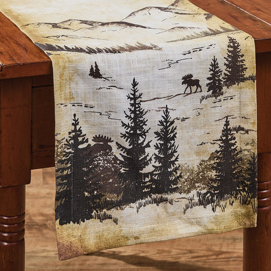 Table runner with moose and pine tree design on a wooden table