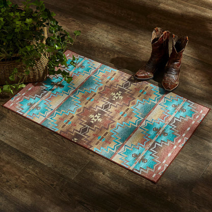 Patterned rug with cowboy boots on a wooden floor next to a plant