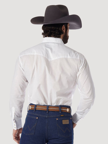 A man shown from behind wearing a white Wrangler western-style long-sleeve shirt, dark blue jeans, a brown studded belt, and a dark brown cowboy hat, against a light gray studio background.