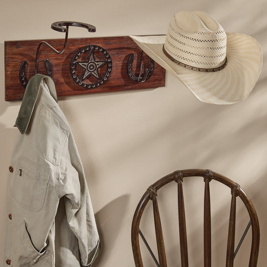 Wooden wall hook with star and horseshoe design, hat, and jacket on a beige wall.