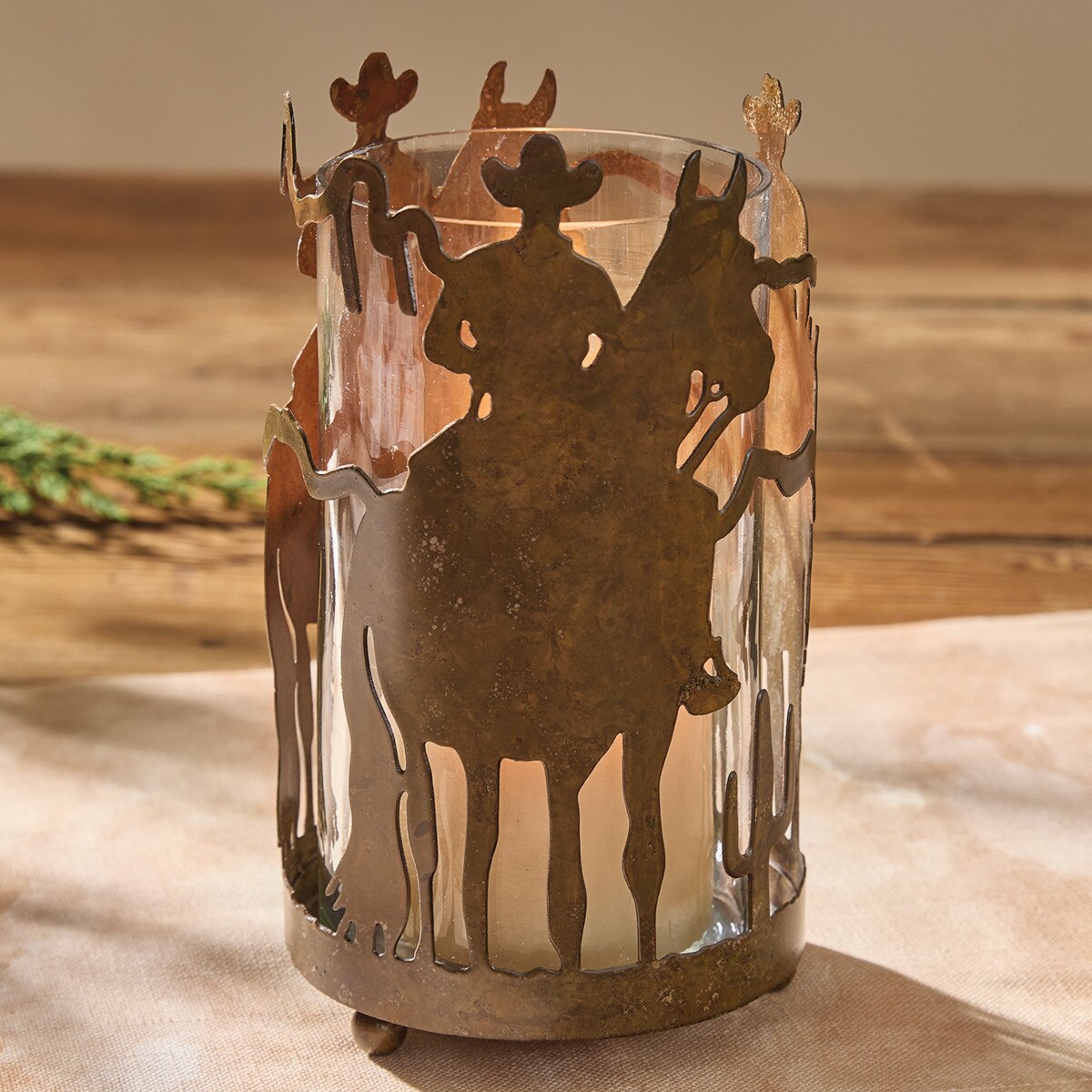 Decorative candle holder with cowboy and horse design on a wooden surface