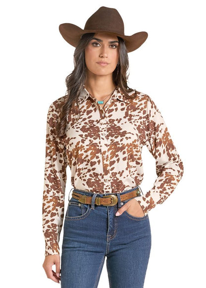 woman wearing a cowhide print shirt from Panhandle Slim and blue jeans and a brown cowboy hat on a white background