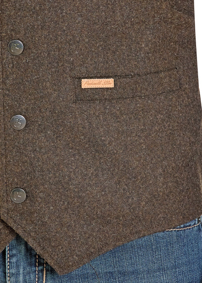 Close-up of a brown wool-blend vest from Panhandle Slim with a buttoned front, a welt pocket, and a small tan brand tab, worn over blue jeans.