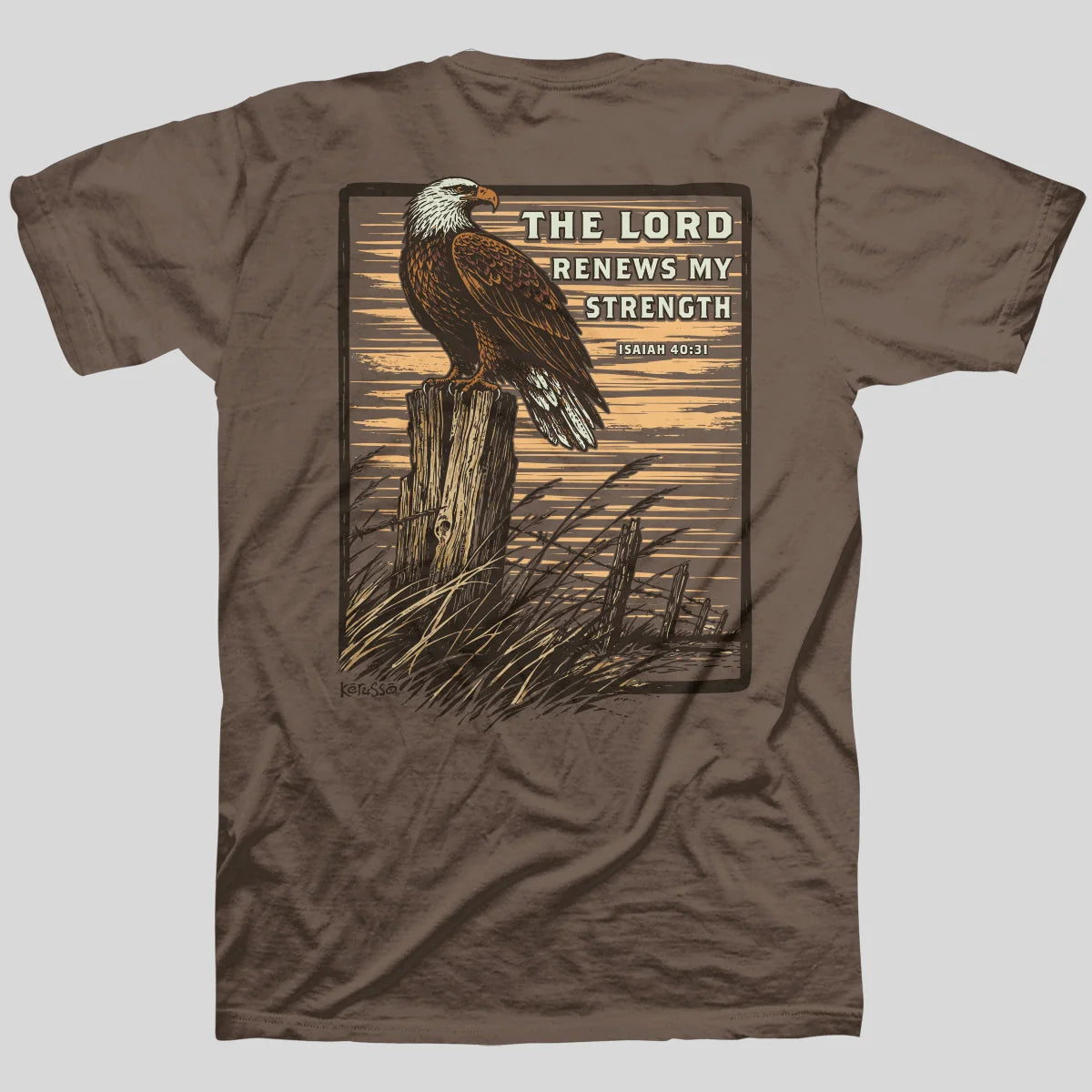 A brown short-sleeve t-shirt from Kerusso with a large graphic print on the back featuring a bald eagle perched on a wooden post with the text 'THE LORD RENEWS MY STRENGTH' and 'ISAIAH 40:31' on a light gray background.
