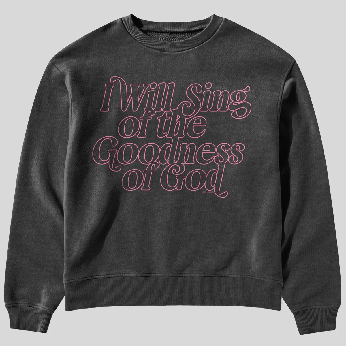 A dark gray crewneck sweatshirt from Kerusso featuring the phrase 'I Will Sing of the Goodness of God' in a pink retro outline font across the chest, displayed on a solid white background.