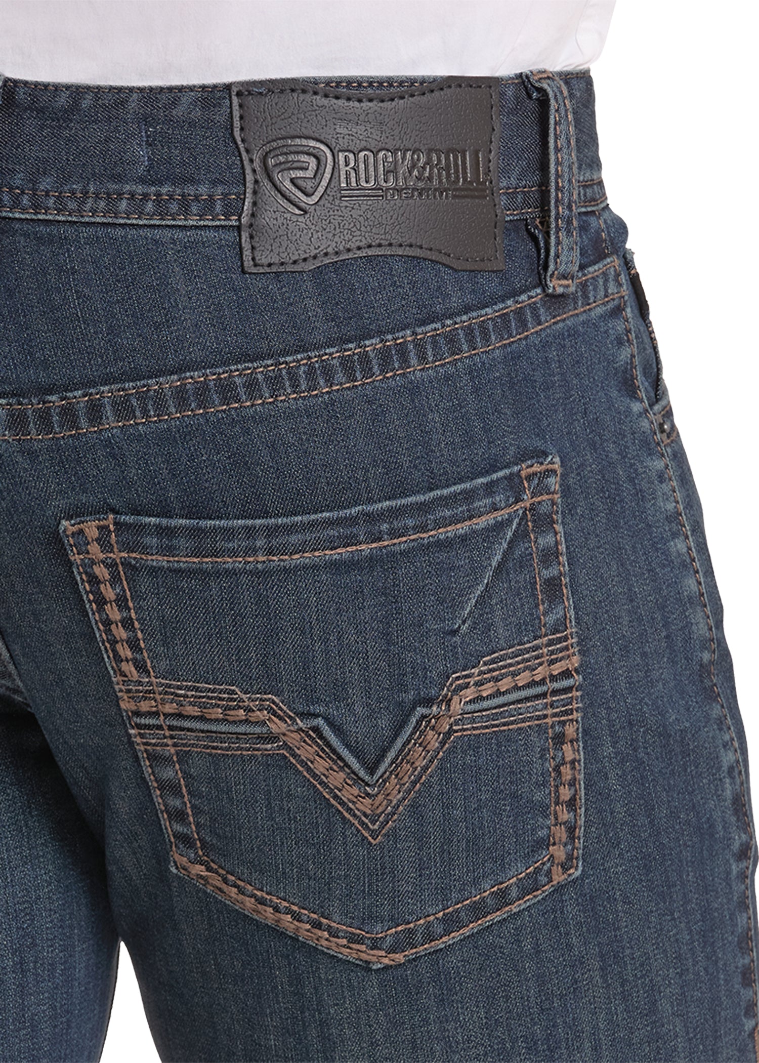 Close-up of the back waistband and pocket area of dark blue denim jeans, showing a Rock & roll brand leather patch on the waistband and contrast stitching.