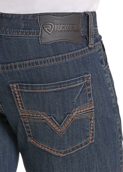 Close-up of the back waistband and pocket area of dark blue denim jeans, showing a Rock & roll brand leather patch on the waistband and contrast stitching.
