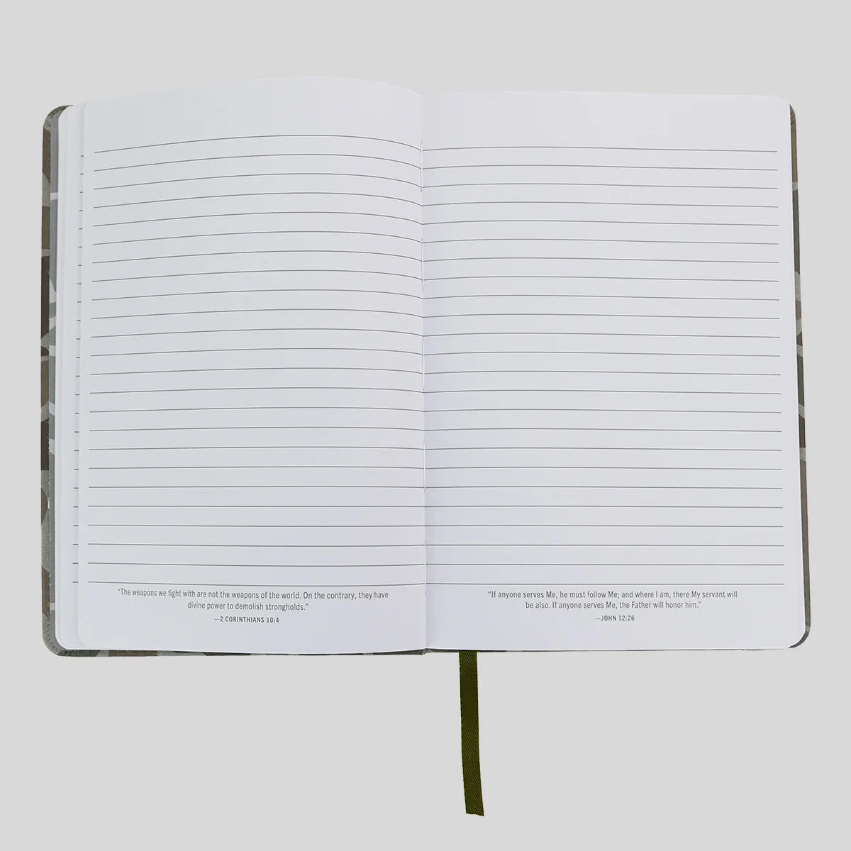 An open lined journal or notebook from Kerusso with blank white pages, small printed verses at the bottom of each page, and a dark olive bookmark ribbon hanging from the center, shown on a light gray background.