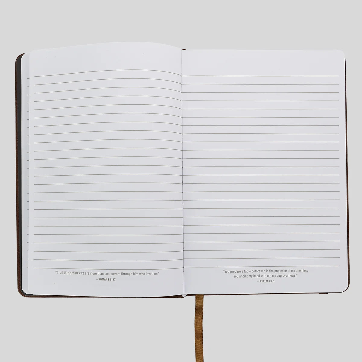 An open lined journal or notebook from Kerusso with a dark cover, blank horizontal ruled pages, and small Bible verse quotes printed at the bottom of each page, shown on a light gray background.