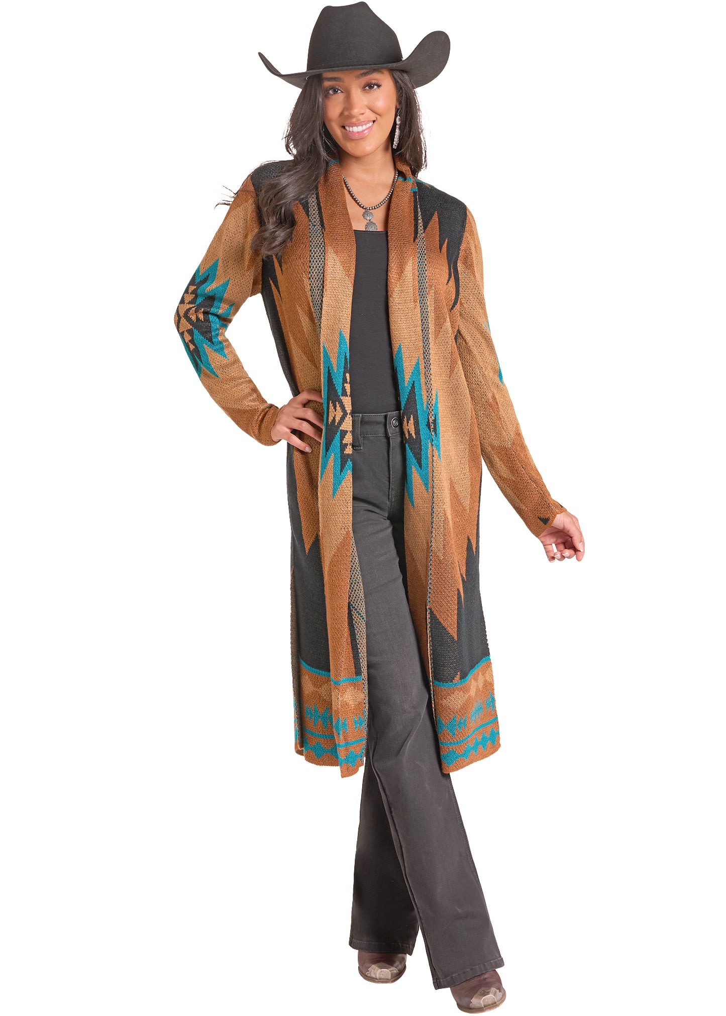 A woman modeling a long Rock&Roll Denim cardigan with Southwestern geometric patterns in turquoise, brown, and black, worn over a black top and dark gray pants, against a plain white background.