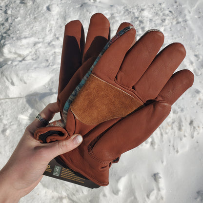 Brown leather gloves held against a snowy background