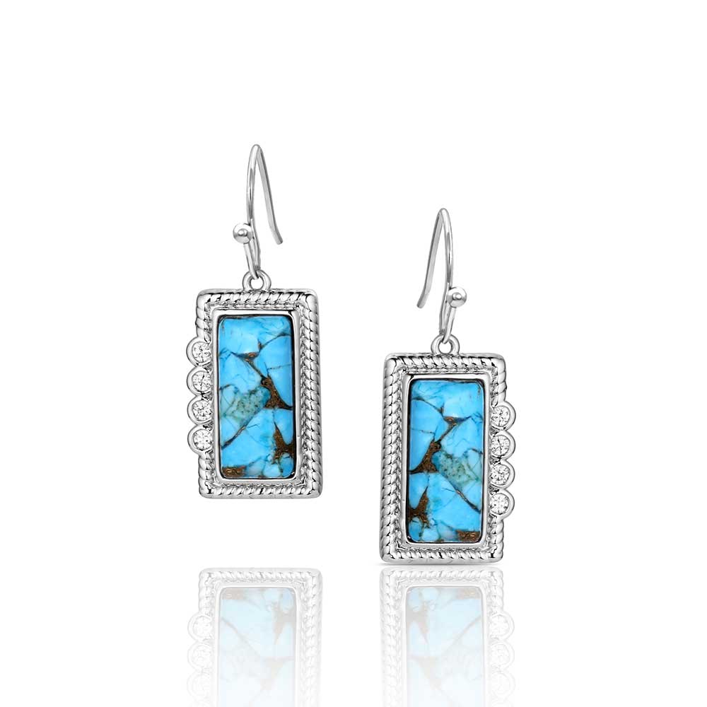 Pair of Montana Silversmiths earrings with turquoise stone and silver frame on a white background
