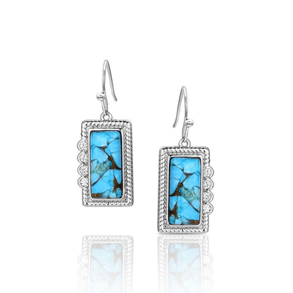 Pair of Montana Silversmiths earrings with turquoise stone and silver frame on a white background