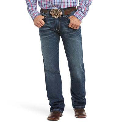 A man wearing a low-rise, turnout men's Ariat jean with a fashion boot cut, relaxed fit through the waist, hip, and thigh, with a visible belt and buckle.