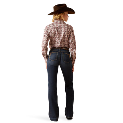 Person wearing a patterned shirt, dark jeans, and a cowboy hat on a white background