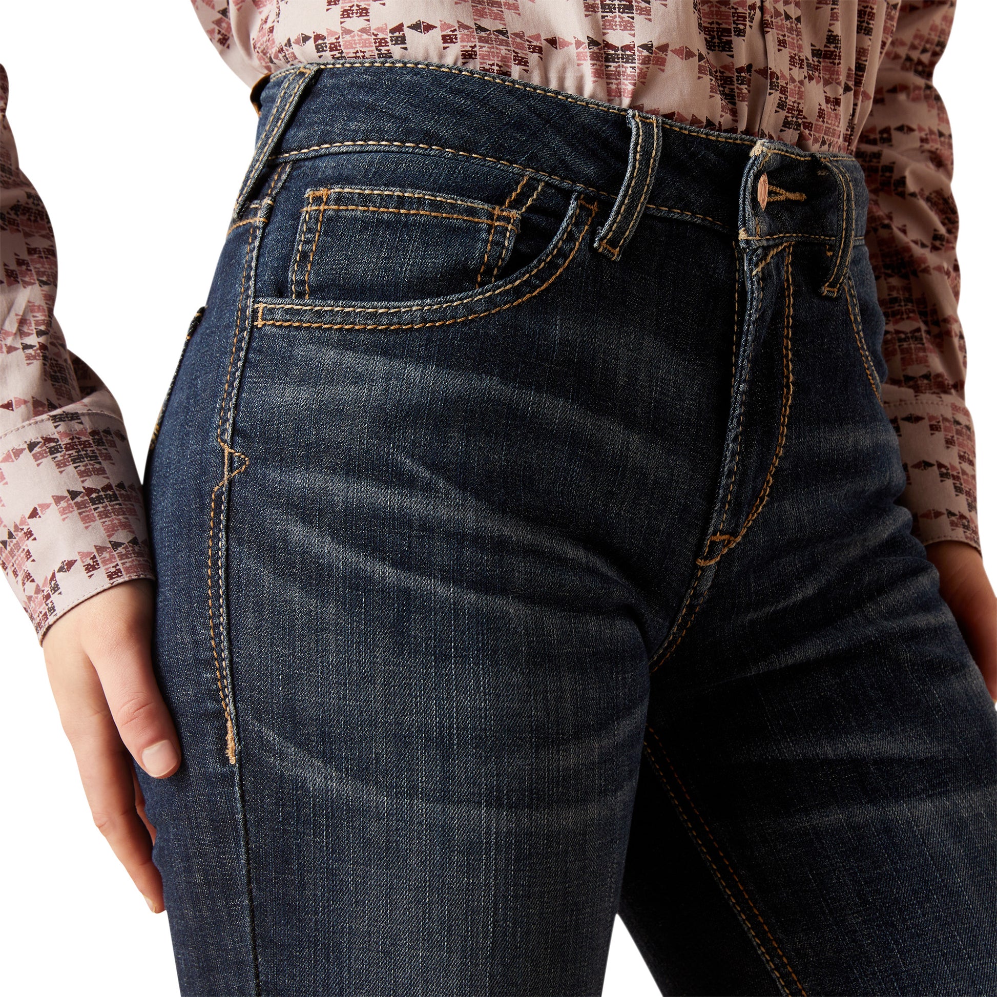 Close-up of dark blue jeans worn by a person with a patterned shirt.