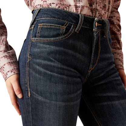 Close-up of dark blue jeans worn by a person with a patterned shirt.