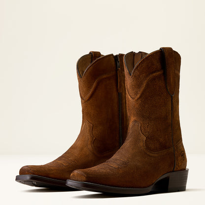 A pair of brown suede cowboy boots with side zippers, shown from a three-quarters angle against a clean, off-white background.