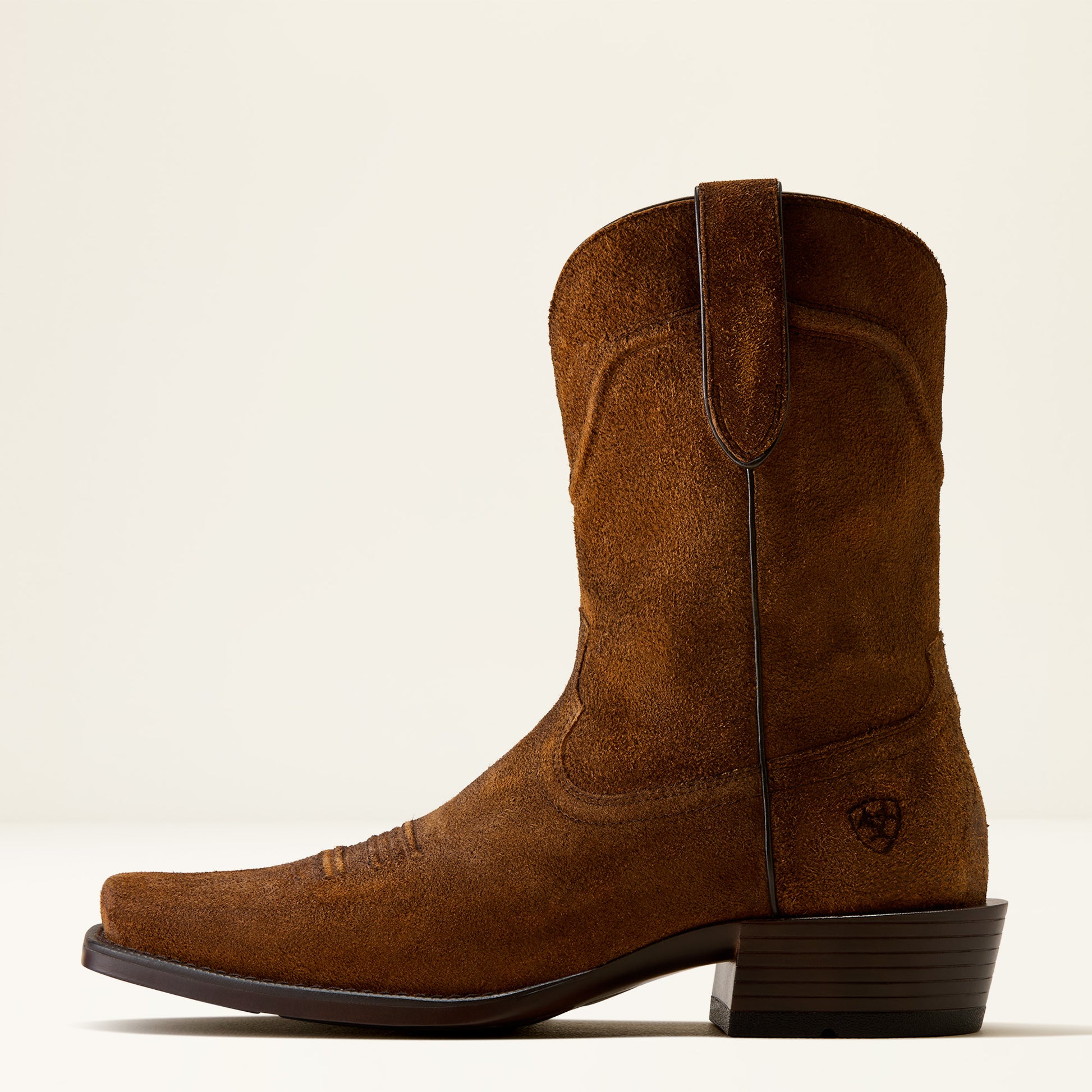A single brown suede cowboy boot with a square toe and dark stacked heel, shown in profile against a clean off-white background.