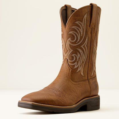 a tan brown wide squre toe cowboy boot by ariat on a off white background