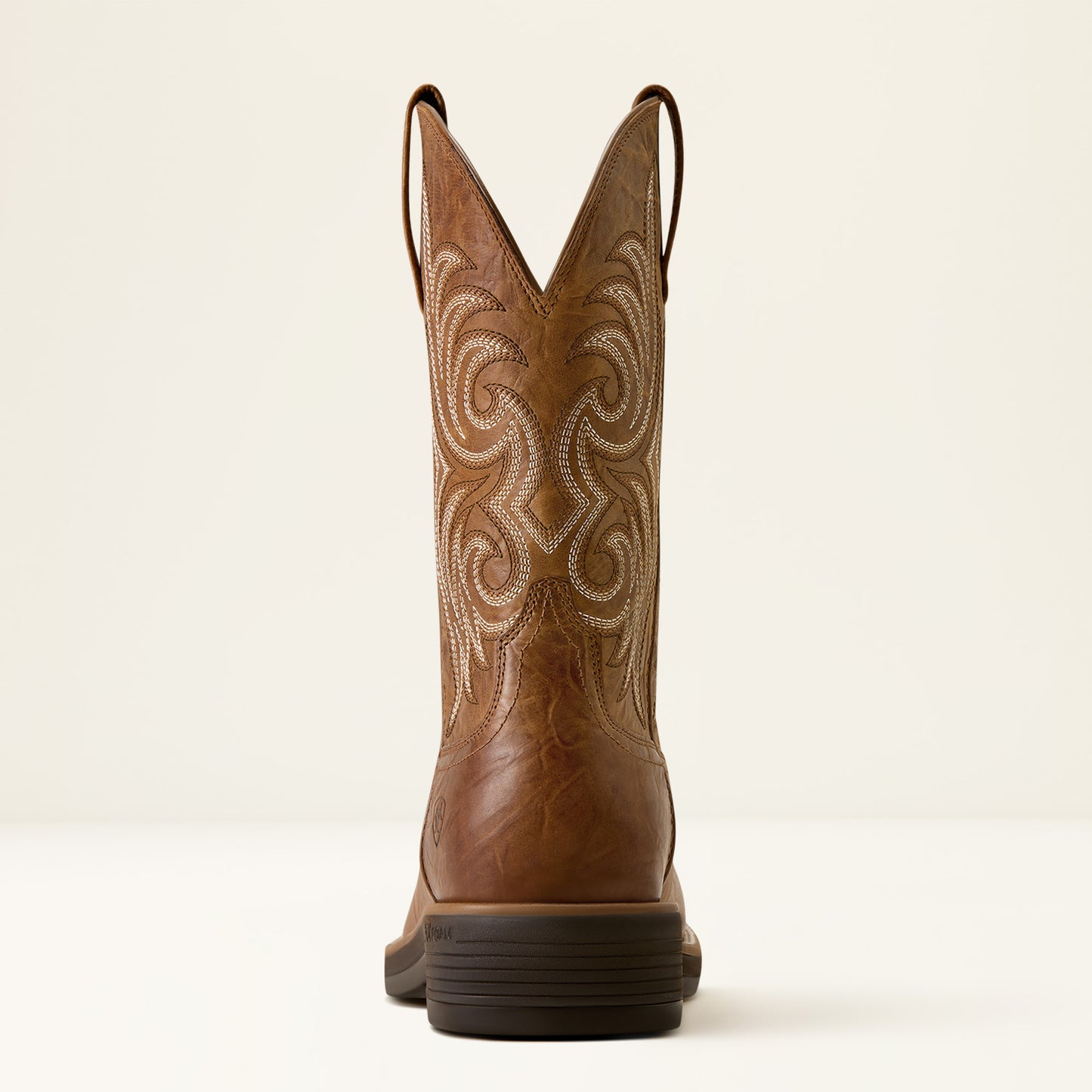 the back of a tan brown wide squre toe cowboy boot by ariat on a off white background