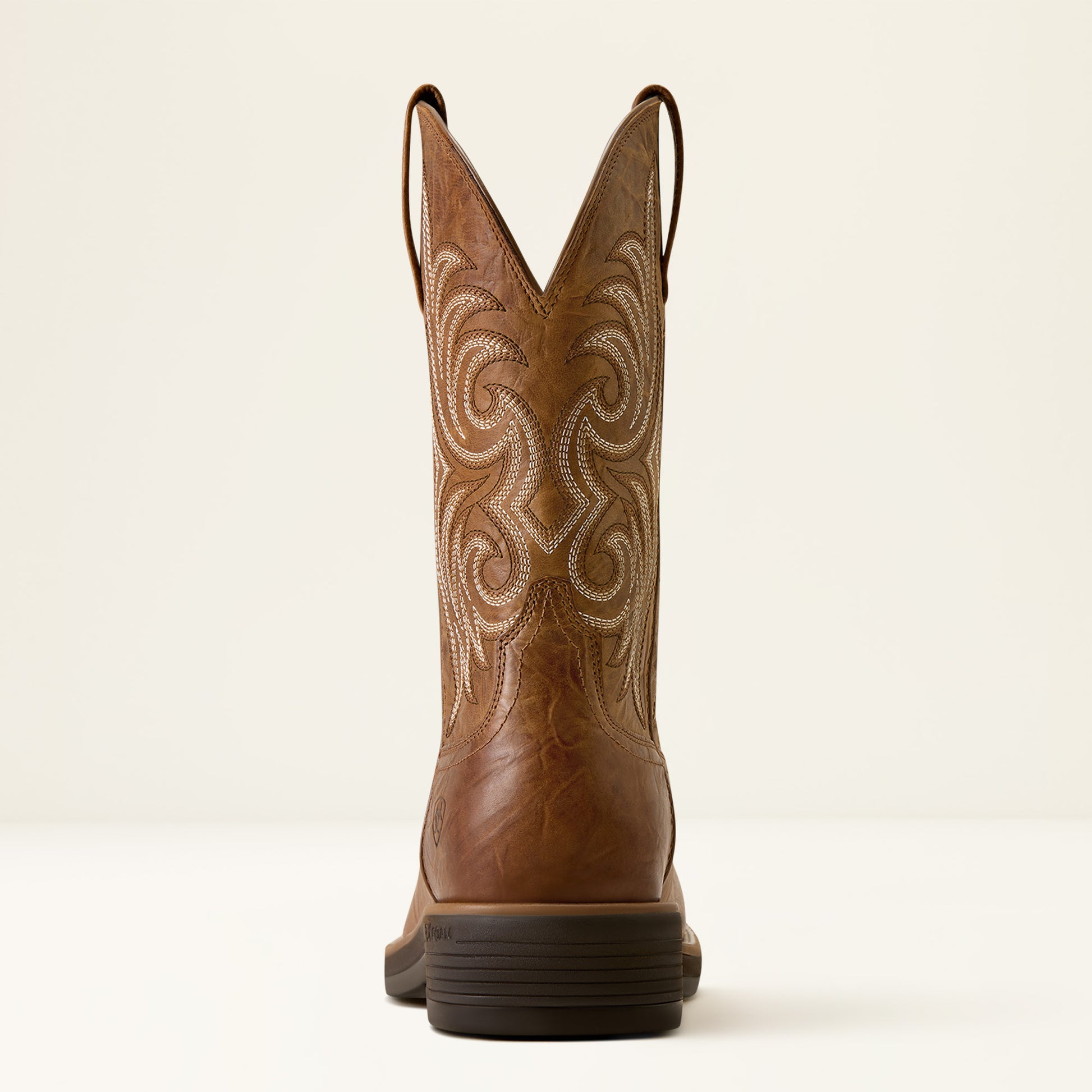 the back of a tan brown wide squre toe cowboy boot by ariat on a off white background
