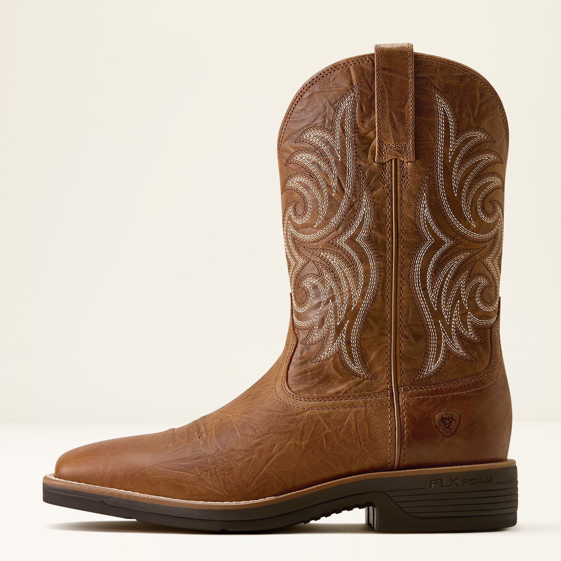 A single brown leather cowboy boot with white embroidered scrollwork on the shaft, shown in a side profile against a light beige background.
