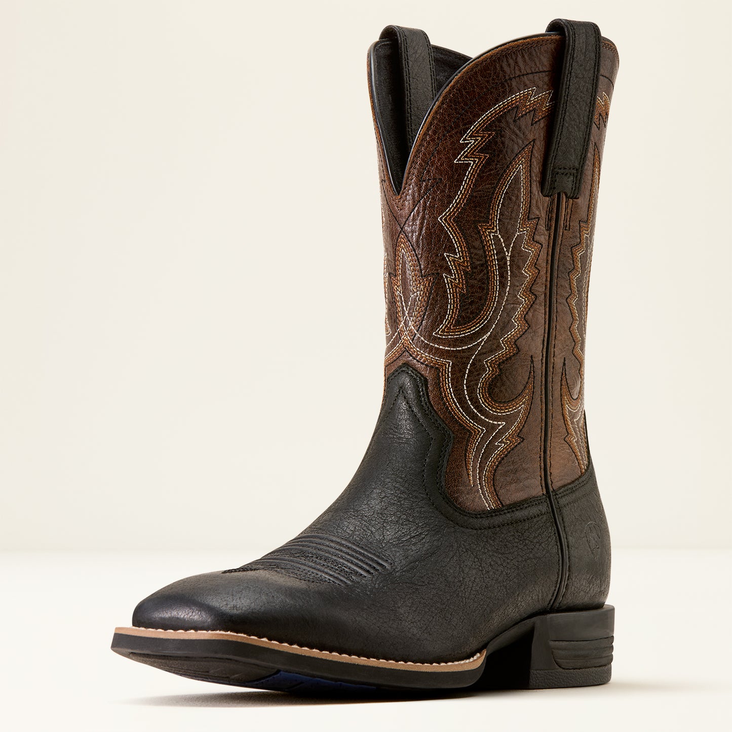 a brown and black wide square toe ariat boot on a cream background