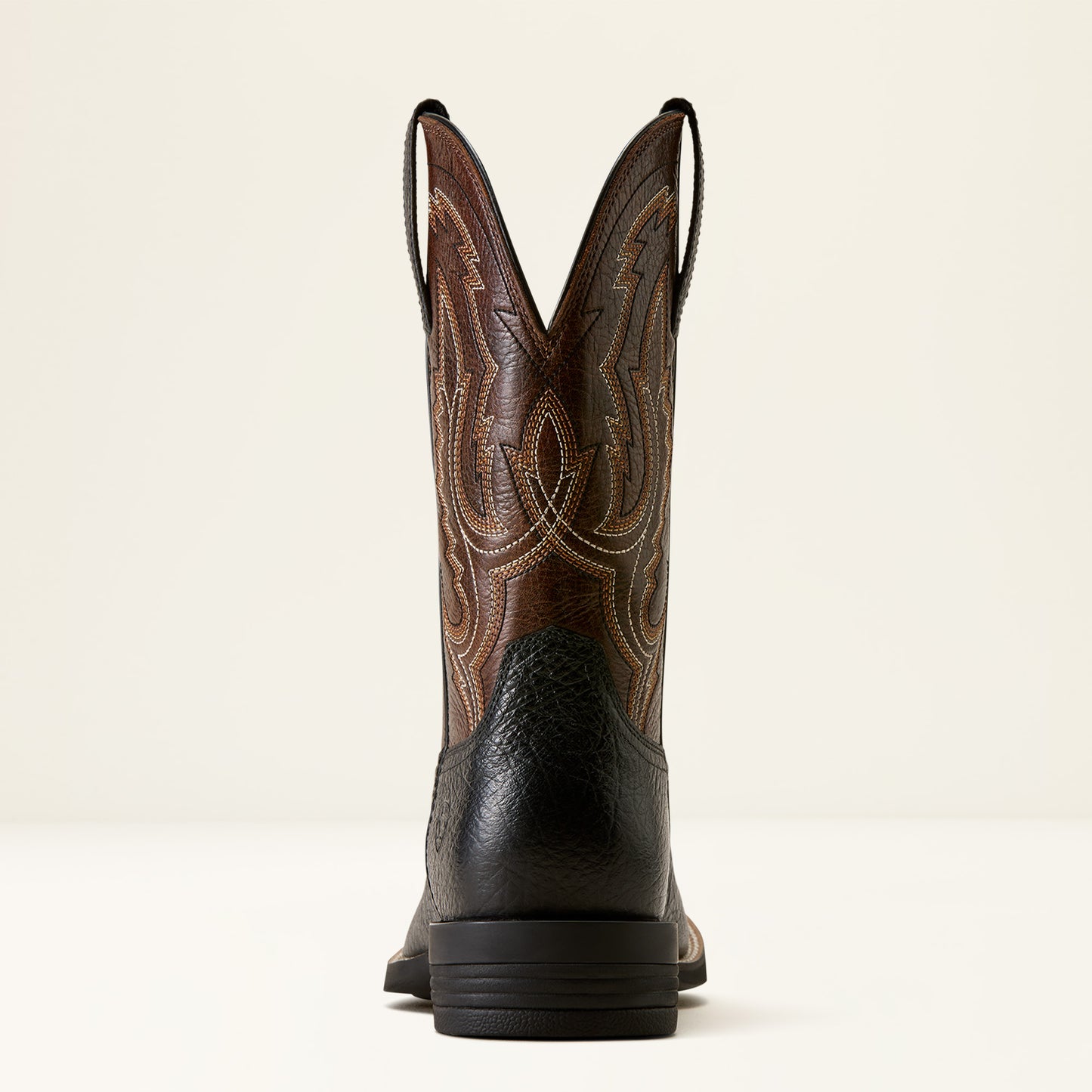 the back of a brown and black wide square toe ariat boot on a cream background