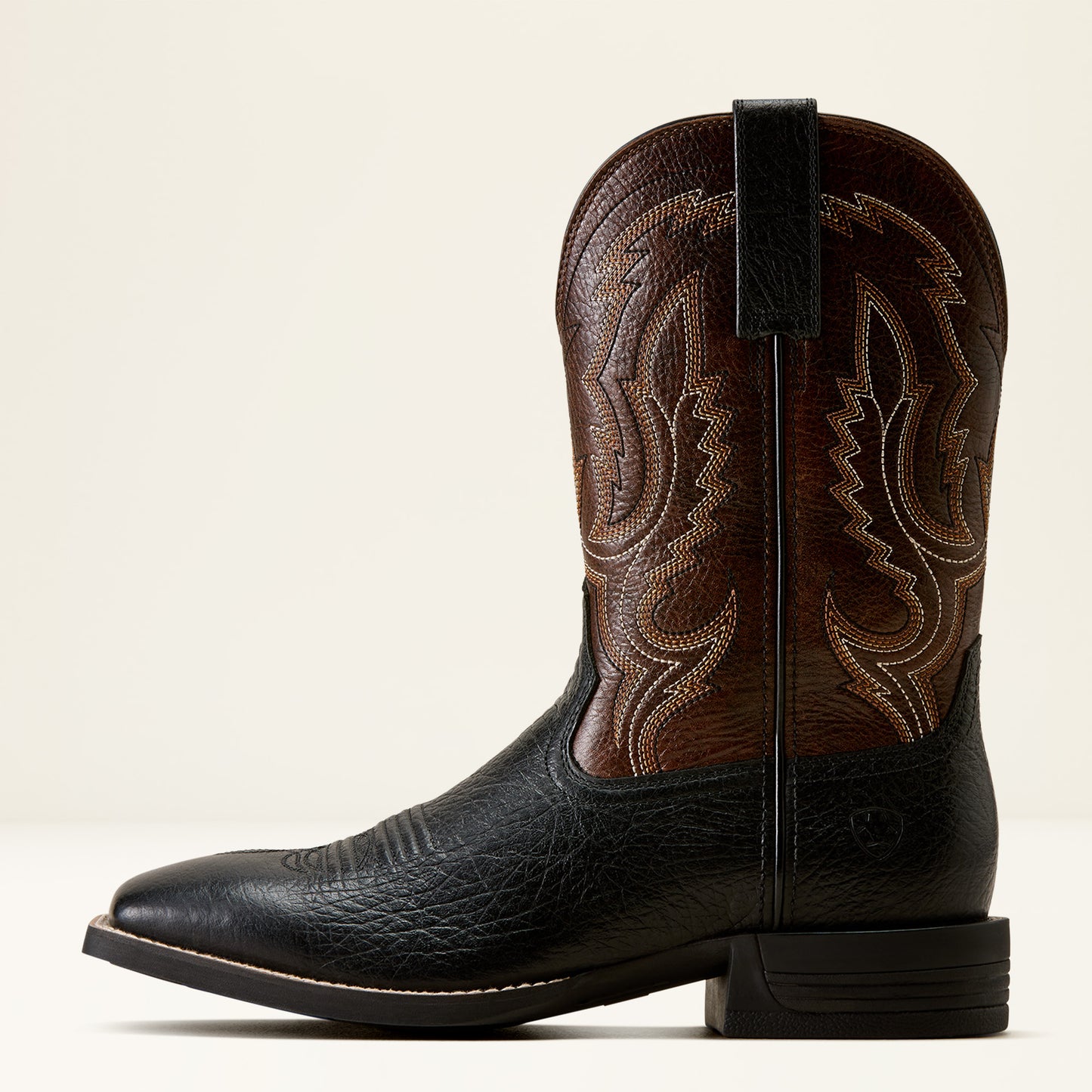 a brown and black wide square toe ariat boot on a cream background