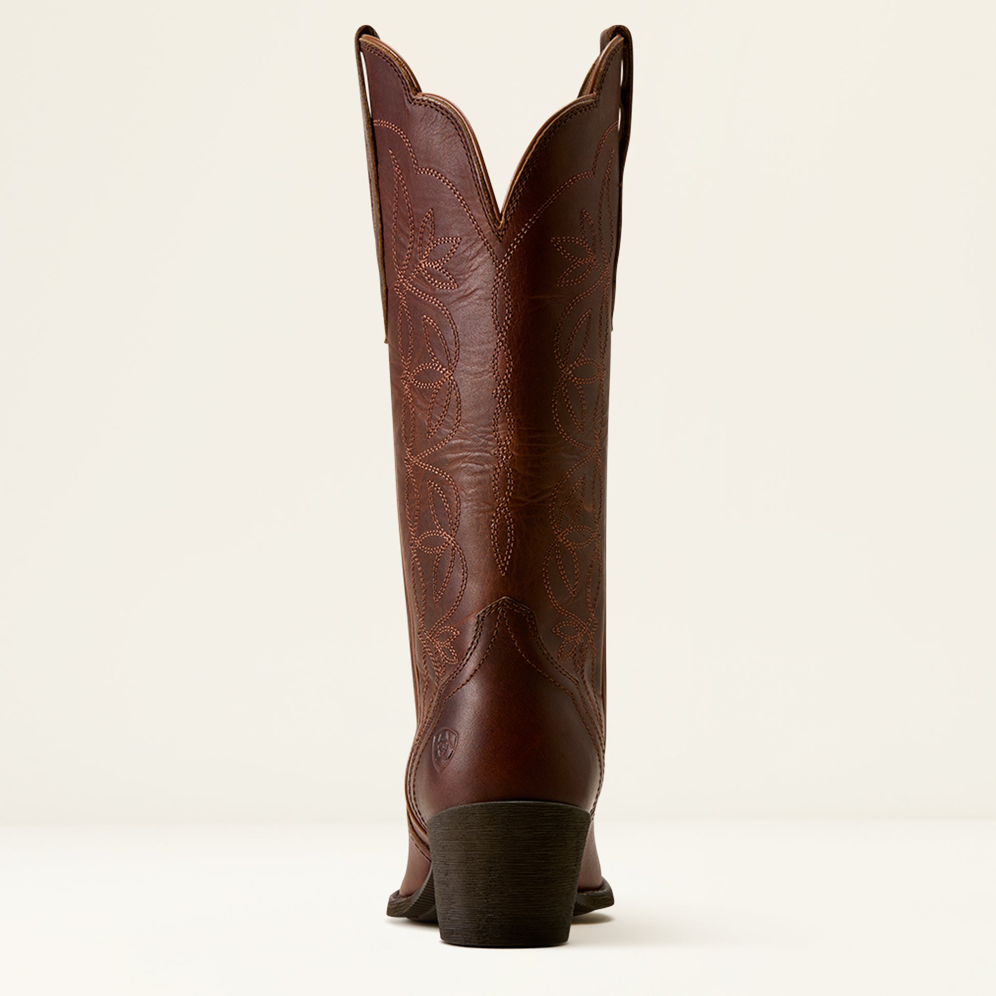 A single brown leather cowboy boot shown from the back, featuring decorative tooling and stitching on the shaft, set against a plain off-white background.