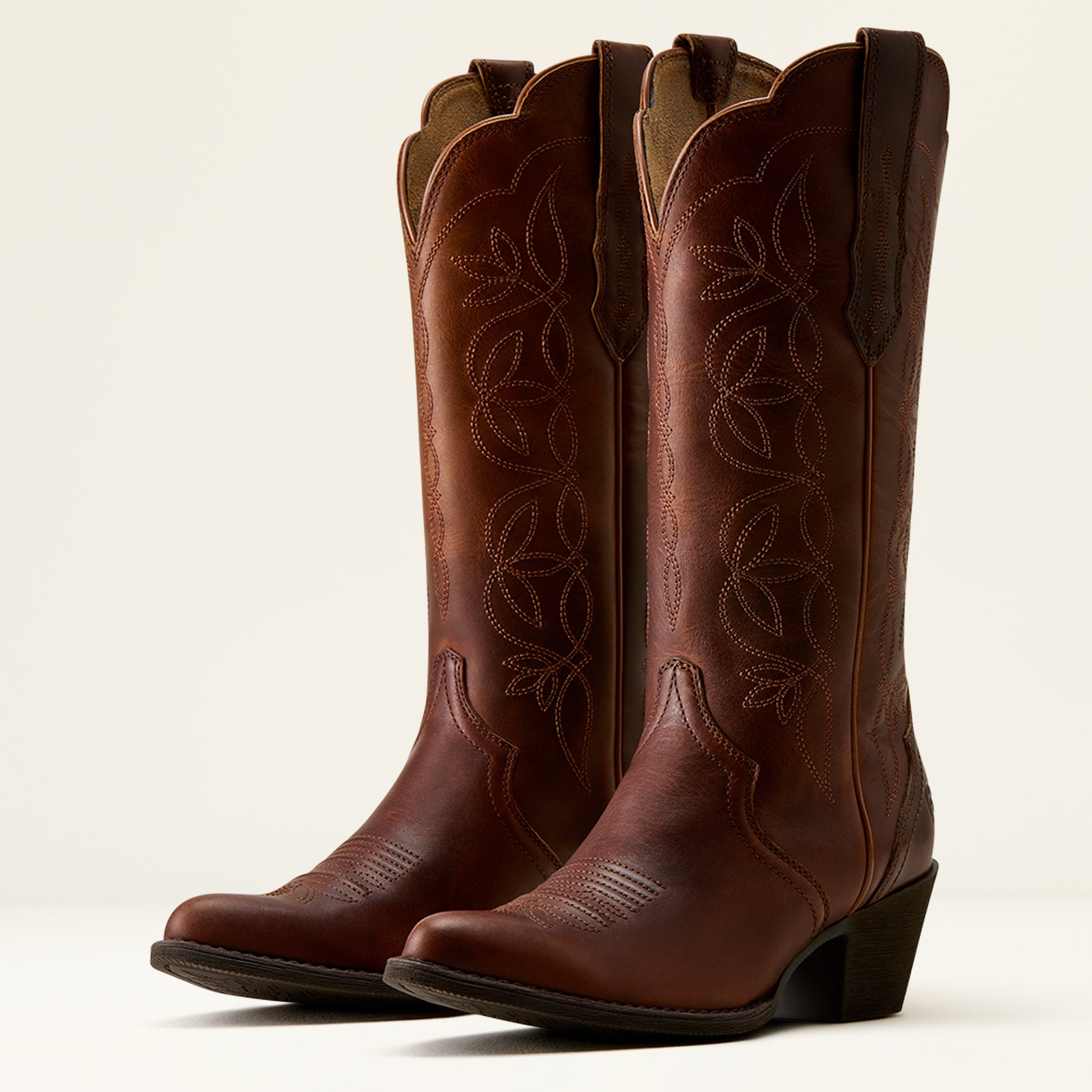 Pair of brown cowboy boots with intricate designs on a white background