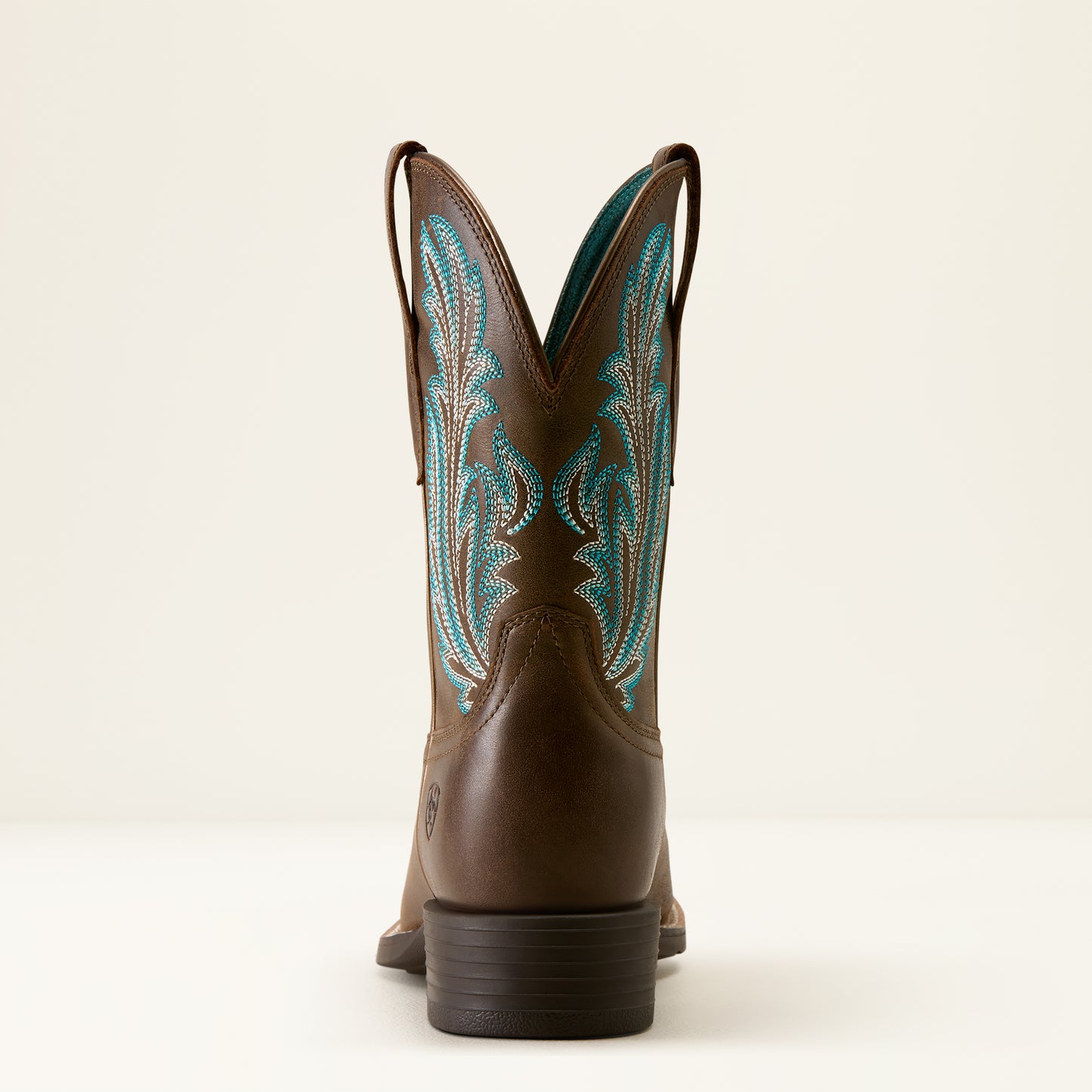 the back of a brown cowboy boot with turquoise stitching