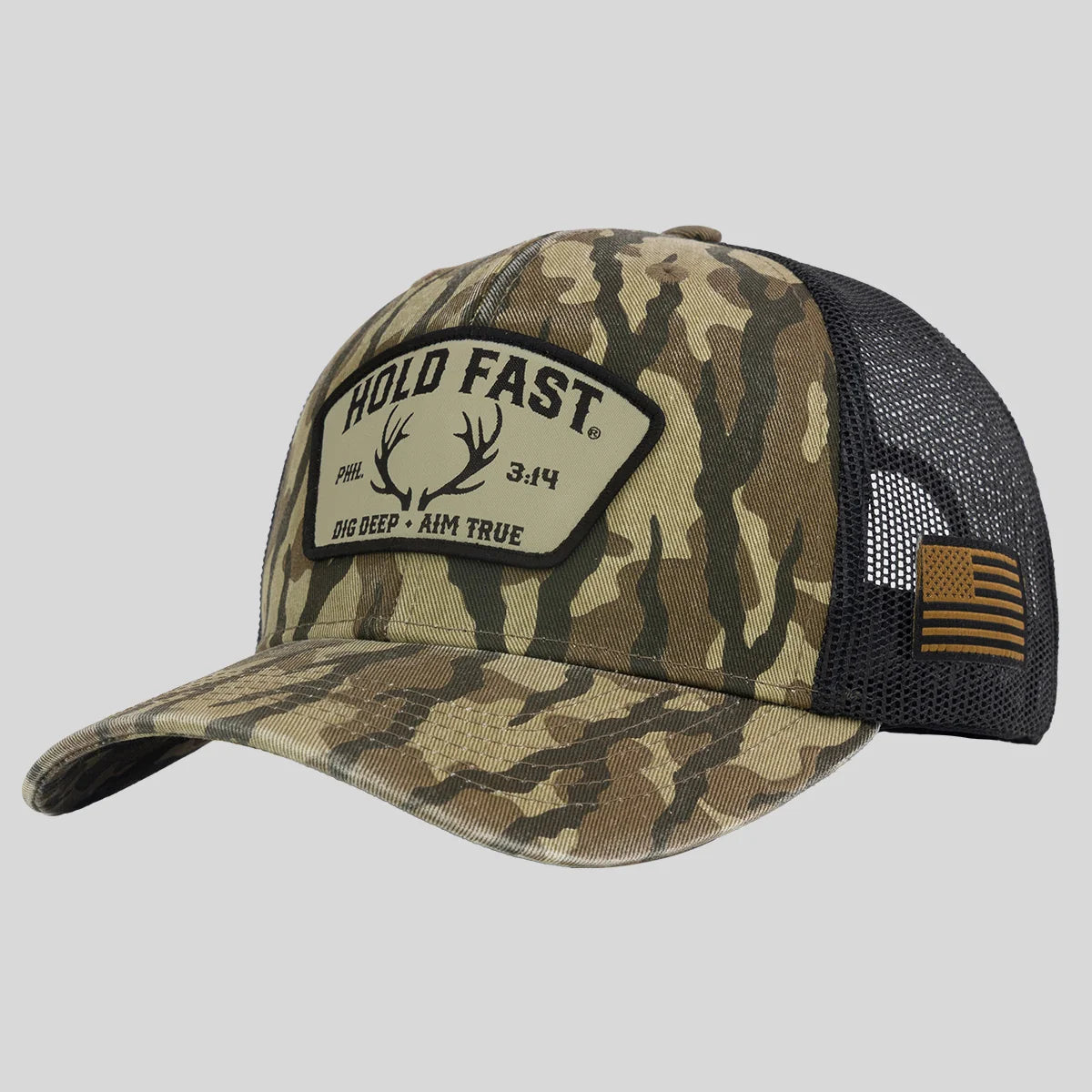 A camouflage trucker hat from Hold Fast with a black mesh back, featuring a front patch that reads 'HOLD FAST 3:14 DIG DEEP * AIM TRUE' and an American flag patch on the side.