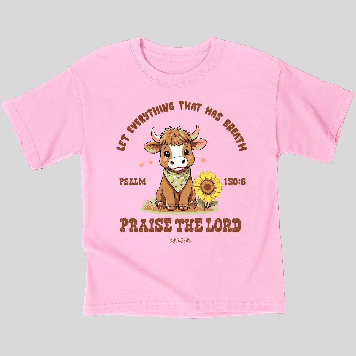 A light pink short-sleeve t-shirt from Kerusso with a cartoon cow graphic and the text 'LET EVERYTHING THAT HAS BREATH PRAISE THE LORD' and 'PSALM 150:6' on a solid light gray background.