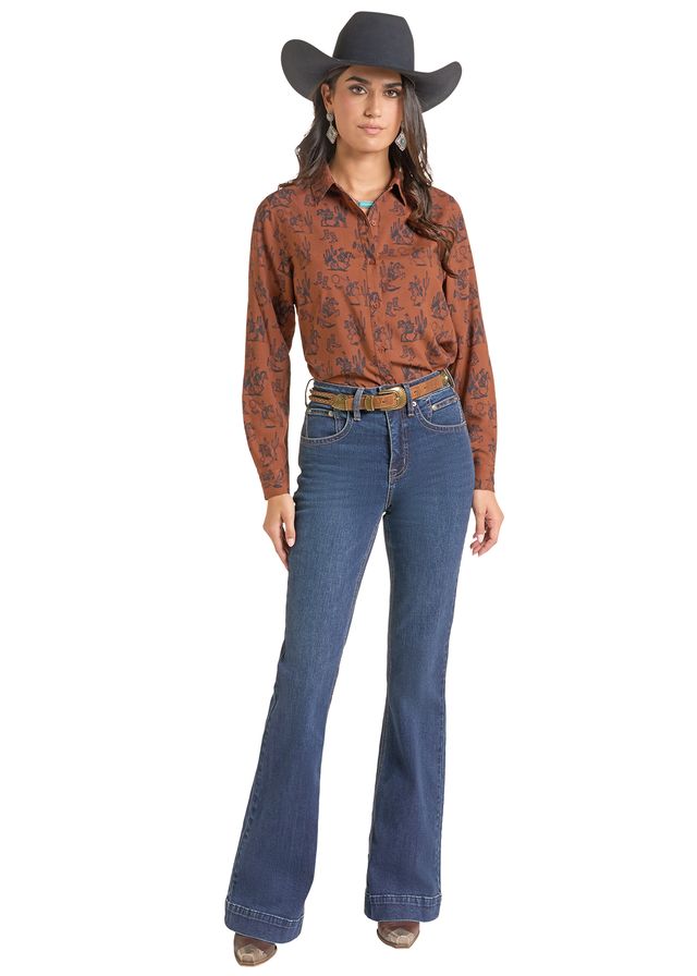 woman wearing a brown Panhandle Slim shirt with print on it, blue jeans and a black cowboy hat on a white background