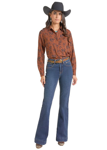 woman wearing a brown Panhandle Slim shirt with print on it, blue jeans and a black cowboy hat on a white background