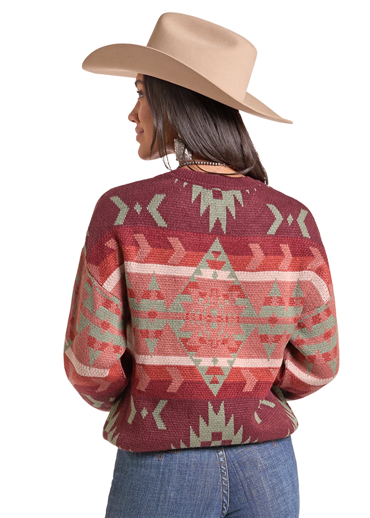  woman wearing a maroon knit sweater by Panhandle Slim with a Southwestern geometric pattern in sage green and beige, paired with a tan cowboy hat and blue jeans, against a plain white background.
