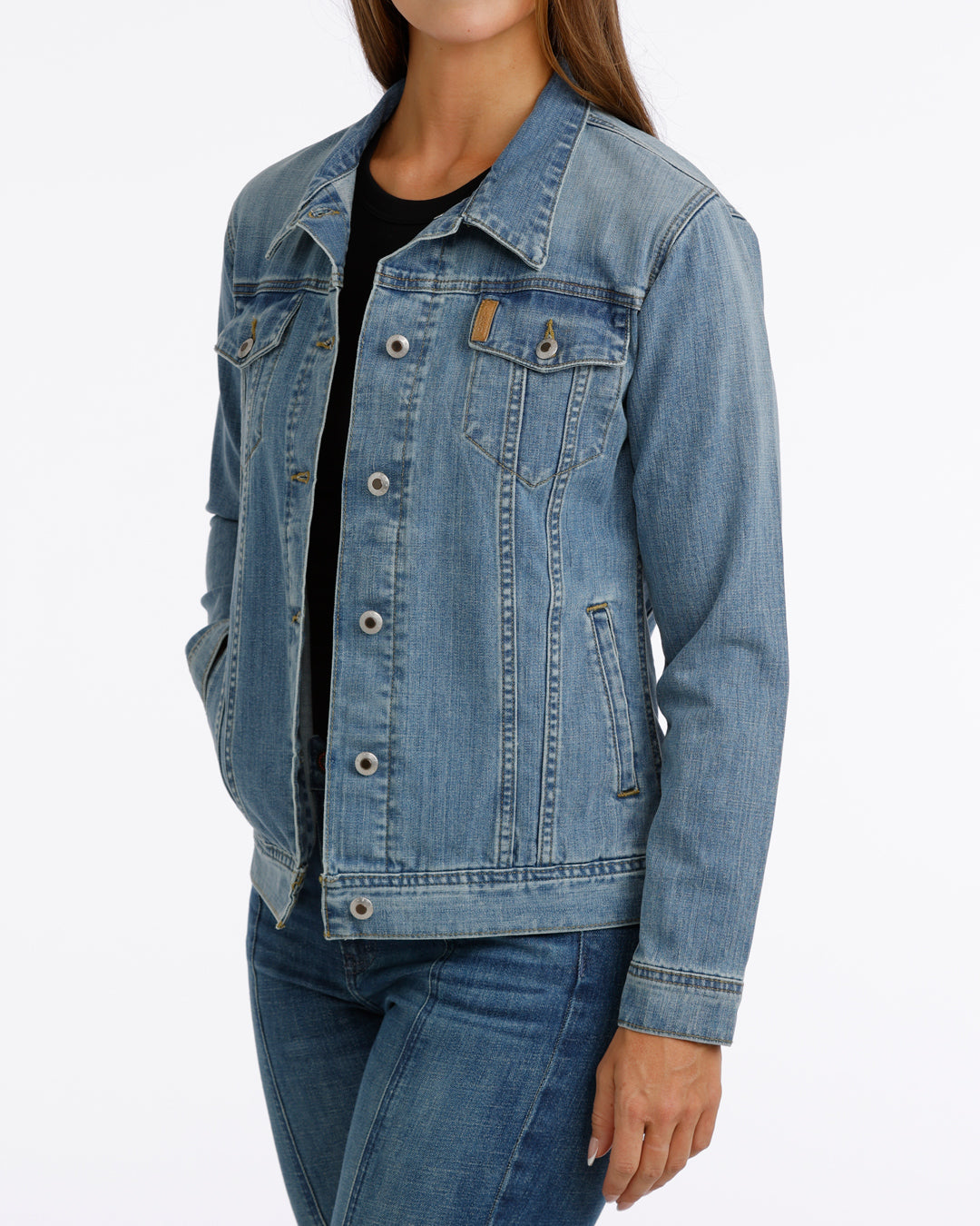 woman wearing a Cinch jean jacket, and blue jeans on a grey background